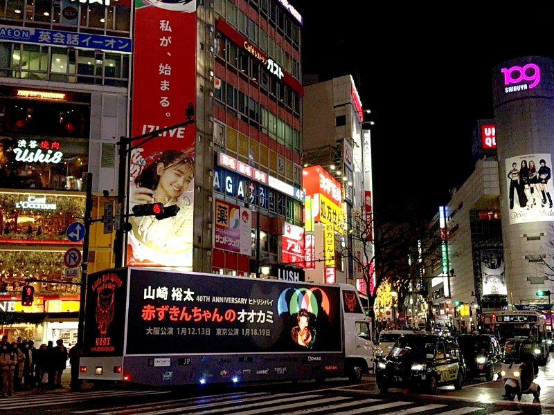 夜の渋谷109周辺を光りながら走るアドトラックの写真